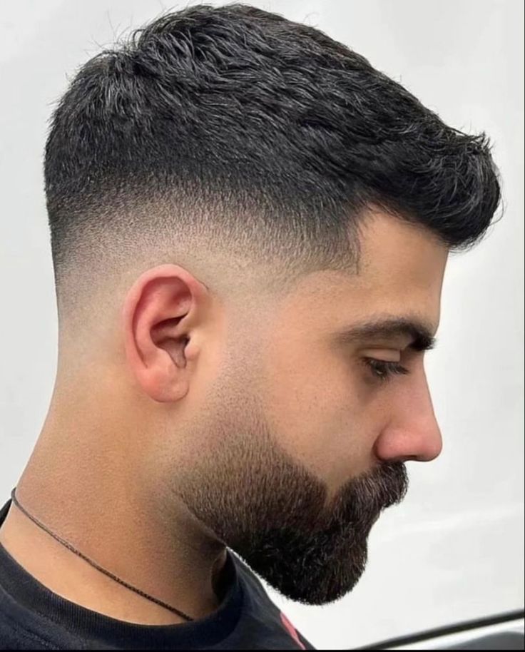Detalle de corte formal masculino con barba corta y patillas difuminadas.