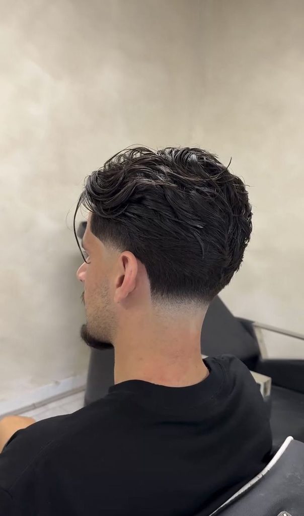 Detalle de corte moderno taper fade para hombre con laterales limpios y textura superior.